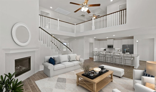 living room with ceiling fan and a towering ceiling