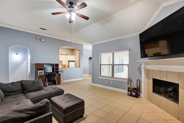 living room with a tiled fireplace, crown molding, vaulted ceiling, and ceiling fan