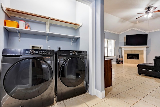 laundry room featuring light tile patterned floors, crown molding, ceiling fan, a tiled fireplace, and separate washer and dryer