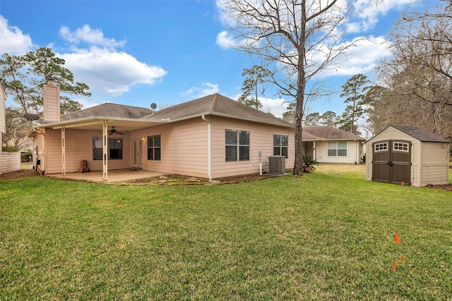 rear view of property featuring a lawn, central AC unit, a shed, and a patio area