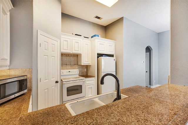 kitchen with sink, backsplash, white cabinets, kitchen peninsula, and white appliances