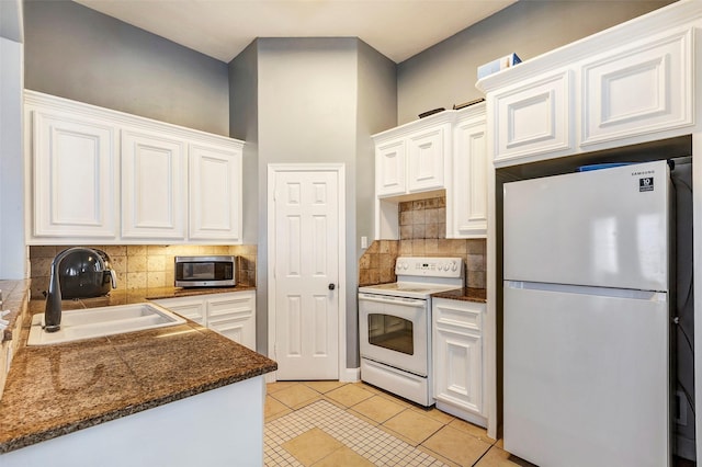 kitchen featuring light tile patterned flooring, sink, white cabinetry, white appliances, and decorative backsplash