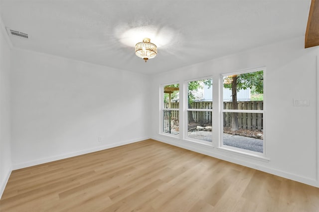 unfurnished room with an inviting chandelier and light hardwood / wood-style flooring