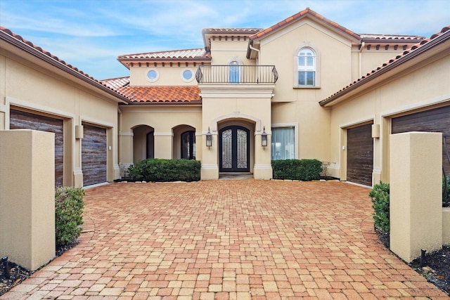 doorway to property with a garage, a balcony, and french doors