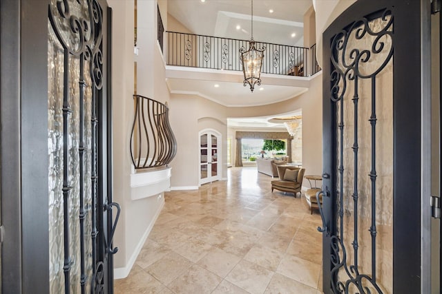 foyer with ornamental molding, a towering ceiling, and a chandelier