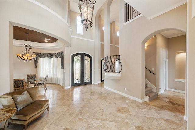 entrance foyer featuring a high ceiling, a tray ceiling, a chandelier, and french doors