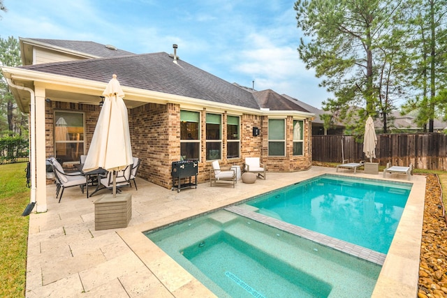 rear view of property with a fenced in pool and a patio area