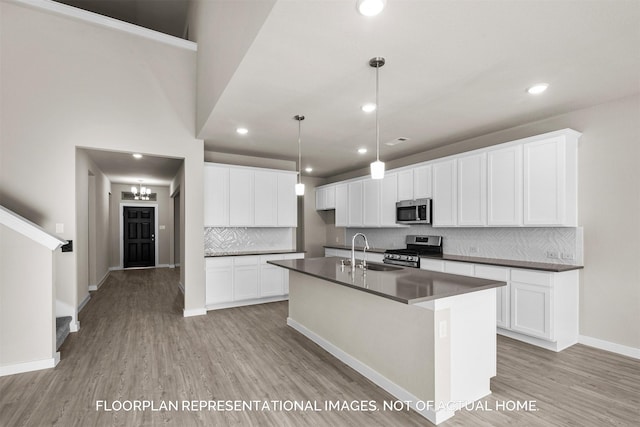 kitchen with pendant lighting, an island with sink, sink, white cabinets, and stainless steel appliances