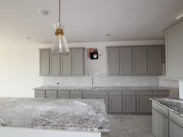 8315 Oceanmist Cove Dr, Cypress, TX 77433 - kitchen with gray cabinets, concrete floors, tasteful backsplash, light stone countertops, and hanging light fixtures