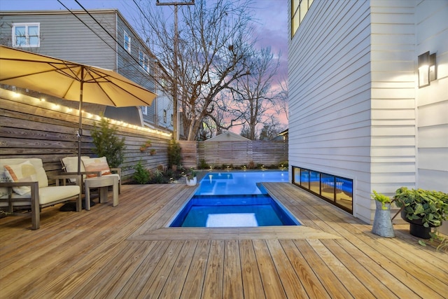 pool at dusk featuring a wooden deck