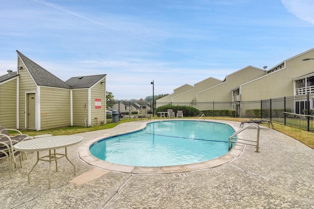 pool with a residential view, fence, and a patio