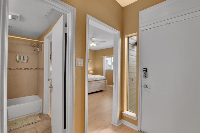 ensuite bathroom featuring baseboards, connected bathroom, shower / tub combination, and wood finished floors