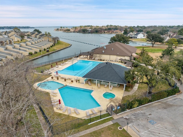 community pool with a water view, fence, and a patio