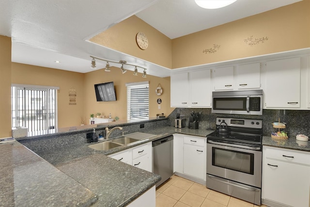 kitchen featuring appliances with stainless steel finishes, dark countertops, a sink, and white cabinetry