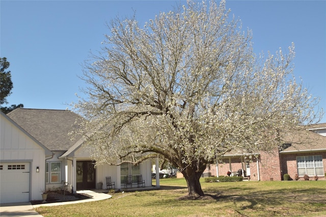 29 Westwood Dr W, Trinity, TX 75862 - view of front facade with a garage, a front lawn, board and batten siding, and a shingled roof