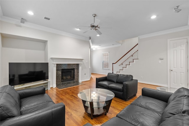 living room with hardwood / wood-style floors, crown molding, a fireplace, and ceiling fan