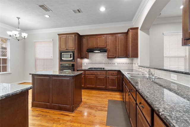 kitchen featuring visible vents, stainless steel microwave, gas cooktop, black oven, and light wood-style floors