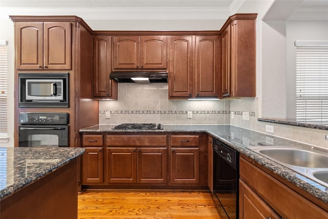 kitchen featuring a sink, black appliances, under cabinet range hood, crown molding, and light wood-type flooring