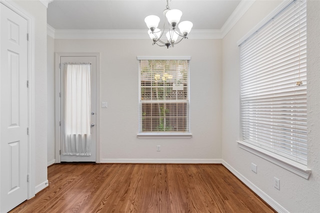 unfurnished dining area with crown molding, an inviting chandelier, and hardwood / wood-style flooring