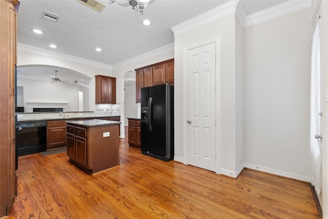 kitchen featuring wood-type flooring, a center island, ceiling fan, black appliances, and crown molding