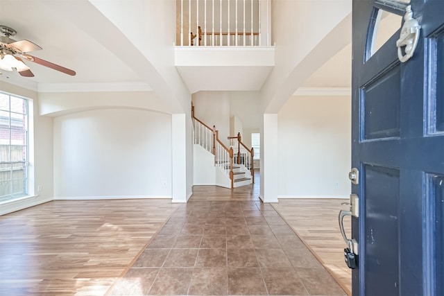 foyer with hardwood / wood-style flooring, crown molding, a towering ceiling, and ceiling fan