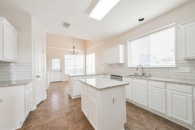 kitchen featuring hanging light fixtures, a kitchen island, sink, and white cabinets