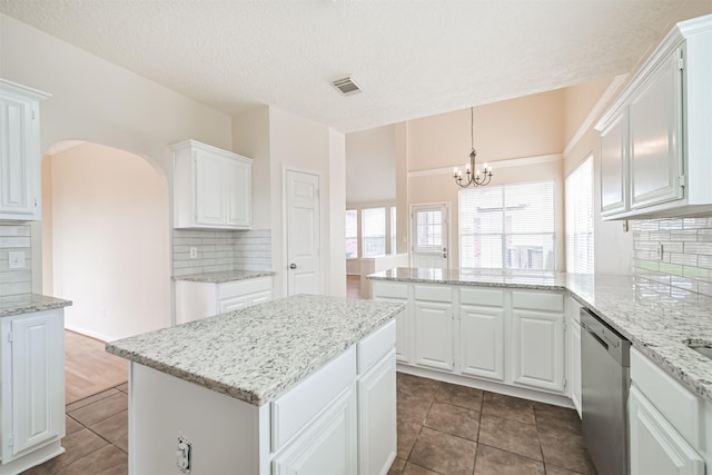 kitchen featuring white cabinetry, decorative light fixtures, stainless steel dishwasher, and a center island