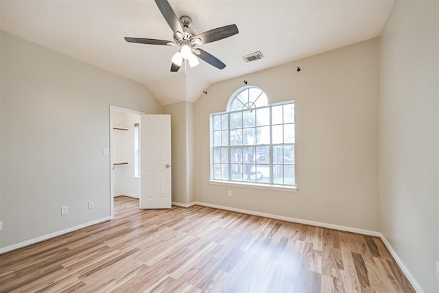 unfurnished bedroom with vaulted ceiling, a spacious closet, ceiling fan, and light hardwood / wood-style flooring