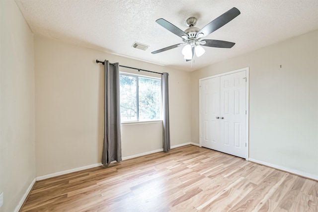 unfurnished bedroom featuring light hardwood / wood-style floors, a closet, and a textured ceiling