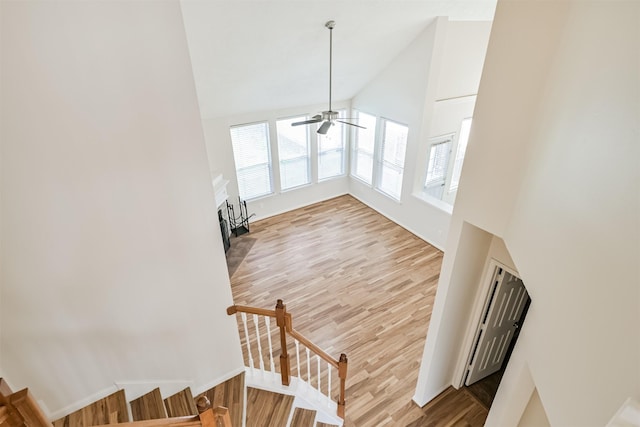 stairway featuring ceiling fan, hardwood / wood-style floors, and high vaulted ceiling