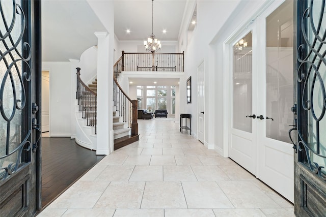 foyer entrance with crown molding, baseboards, stairway, and a chandelier