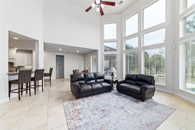 living room featuring a wealth of natural light, light tile patterned floors, baseboards, and ceiling fan