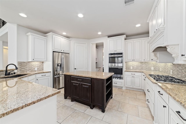kitchen featuring visible vents, appliances with stainless steel finishes, light stone counters, a sink, and decorative backsplash