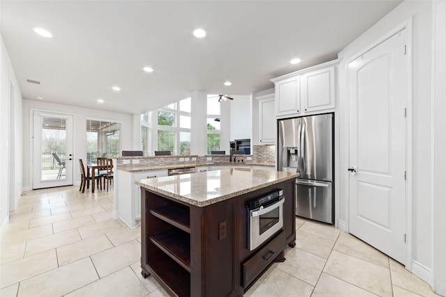 kitchen with light tile patterned floors, open shelves, a peninsula, and stainless steel appliances