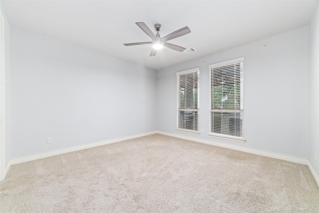 carpeted spare room with visible vents, baseboards, and ceiling fan