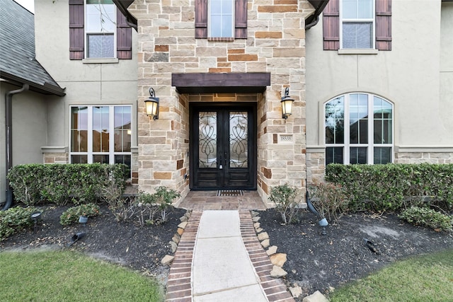 view of exterior entry with stucco siding and stone siding
