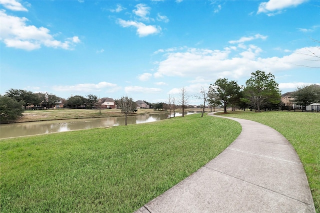 view of property's community with a water view and a lawn