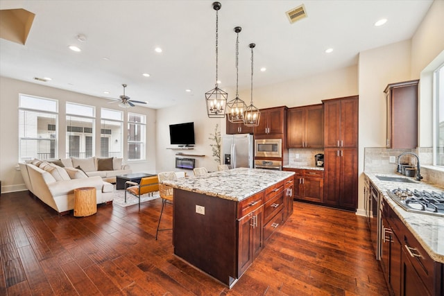 kitchen with appliances with stainless steel finishes, a center island, sink, and light stone countertops