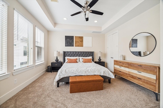 carpeted bedroom with ceiling fan and a tray ceiling