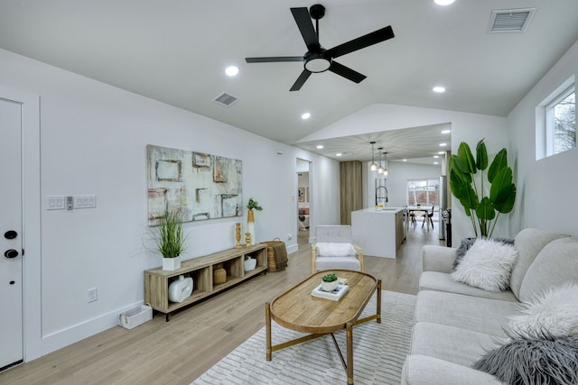 living room featuring sink, vaulted ceiling, light hardwood / wood-style floors, and ceiling fan