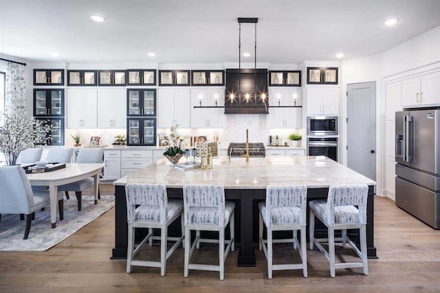 kitchen featuring wall chimney exhaust hood, white cabinets, recessed lighting, a large island, and appliances with stainless steel finishes