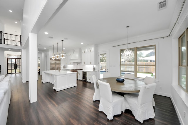 dining room featuring wine cooler, dark wood-type flooring, visible vents, baseboards, and an inviting chandelier