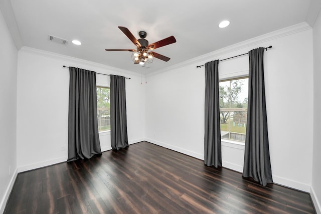 empty room featuring dark wood-style floors, visible vents, crown molding, and baseboards