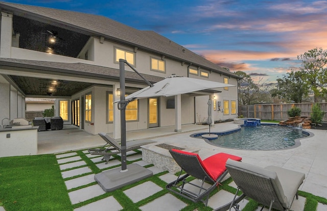 back of house at dusk featuring a fenced in pool, a patio area, a fenced backyard, and stucco siding