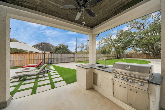 view of patio / terrace featuring a fenced backyard, a ceiling fan, grilling area, and exterior kitchen