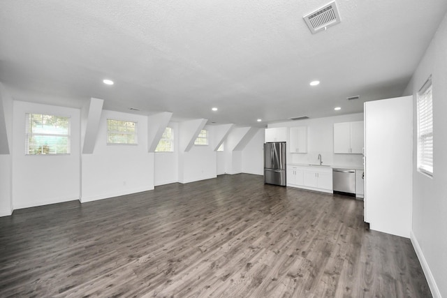 unfurnished living room featuring a textured ceiling, recessed lighting, a sink, visible vents, and dark wood-style floors