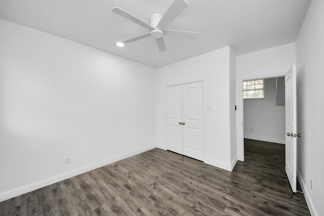 unfurnished bedroom with a closet, dark wood finished floors, a ceiling fan, and baseboards