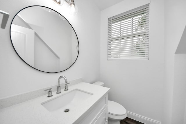 bathroom with toilet, baseboards, and vanity