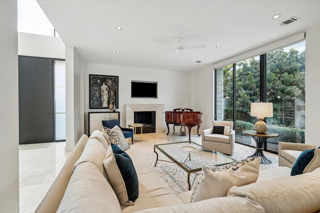 tiled living room featuring ceiling fan, floor to ceiling windows, and a fireplace