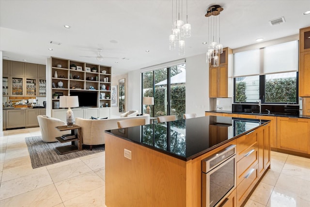 kitchen with a kitchen island, decorative light fixtures, sink, dark stone countertops, and oven